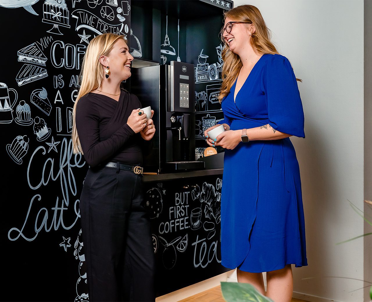 Zijaanzicht twee dames met een kop koffie in gesprek met elkaar