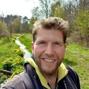 Sander Staal, foto van de voorkant man lachend natuur op de achtergrond